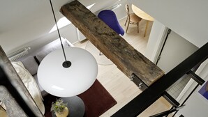 A modern interior with a staircase, a round white table, a blue chair, and a wooden beam structure. - Attic Studio Apartment for 2 (København)