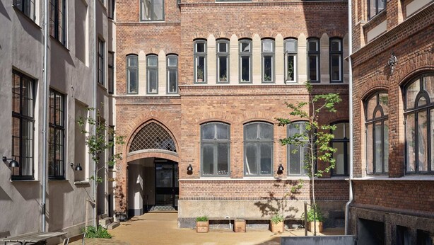 A courtyard with a brick building, benches, and potted plants. - One-Bedroom Apartment for 3 (København)
