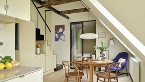 A modern kitchen with a dining area, wooden chairs, a table, and a blue chair.