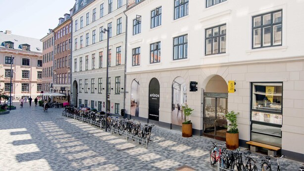 A cobblestone street with a row of historic buildings, a café, and bicycles parked along the sidewalk.