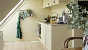 A compact kitchen with a built-in oven, a hanging plant, and a coffee maker on the counter.