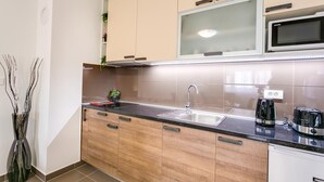 Eine moderne Küche mit Holzschränken, einer Edelstahlspüle, einer Mikrowelle und einer Kaffeemaschine.