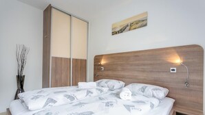 Ein Schlafzimmer mit einem hölzernen Kopfteil, einem Bett mit weißer Bettwäsche mit architektonischen Drucken, einem Nachttisch, einer Wandlampe und einem Bild über dem Bett.