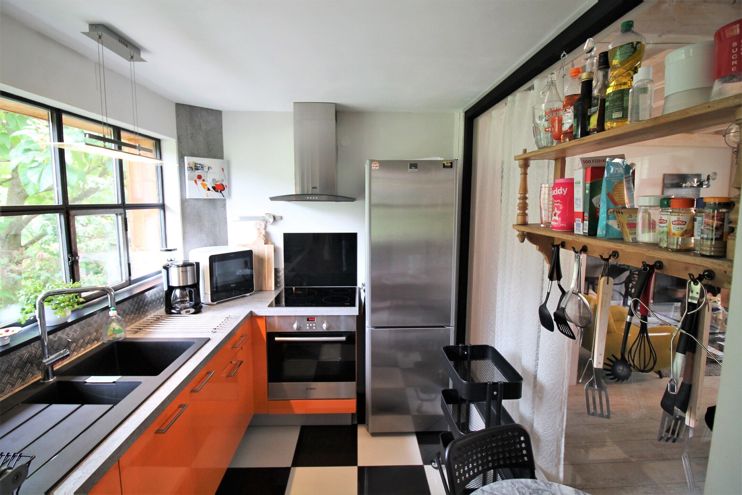 A kitchen with a double sink, oven, microwave, and stainless steel refrigerator.