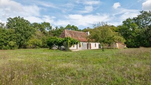 A rustic house with a sloped roof, surrounded by a grassy field and trees. - Tranquil Escape in Cendrieux (Val de Louyre et Caudeau)