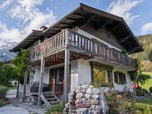 A chalet-style house with a wooden balcony, stone steps, and a view of mountains. - Chalet in ski Area in Leogang (Leogang)