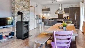 A modern kitchen with a stone accent wall, a built-in oven, and stainless steel appliances. - Chalet in ski Area in Leogang (Leogang)