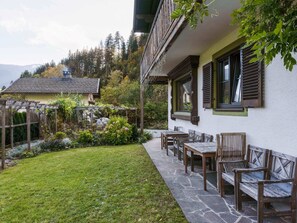 A patio area with stone flooring, wooden benches, and a garden with various plants and a small pond. - Chalet in ski Area in Leogang (Leogang)
