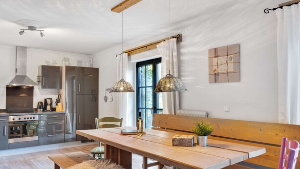 A modern kitchen with stainless steel appliances, a wooden dining table, and a bench. - Chalet in ski Area in Leogang (Leogang)