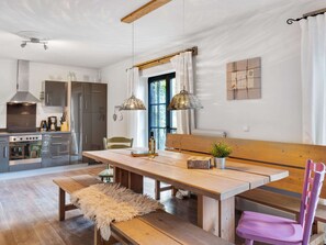 Une cuisine moderne équipée d’appareils électroménagers en acier inoxydable, avec une table à manger en bois et un banc.