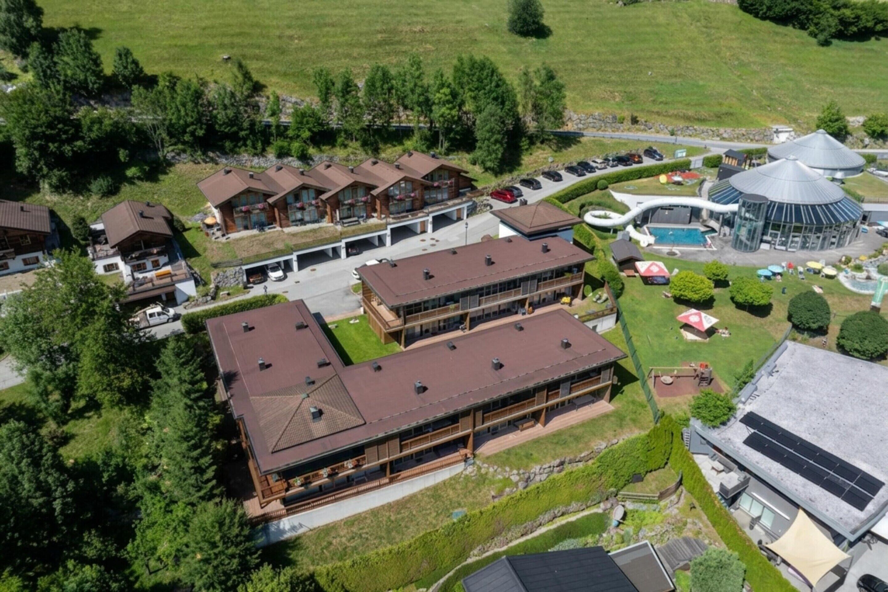 A multi-story hotel with a central courtyard, a swimming pool, and a covered outdoor area.