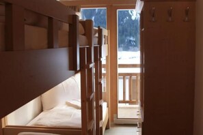 A room with a bunk bed, a wooden door leading to a balcony, and a view of snow outside. - Alpine Chalet With Balcony & Sauna (Wald im Pinzgau)