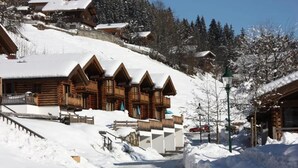 A snow-covered mountain lodge with multiple wooden cabins, a ski lift, and a clear sky. - Alpine Chalet With Balcony & Sauna (Wald im Pinzgau)