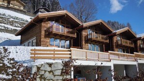 A chalet-style building with multiple balconies, a stone retaining wall, and a car parked in the driveway. - Alpine Chalet With Balcony & Sauna (Wald im Pinzgau)
