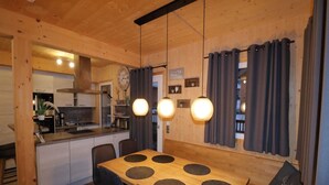 Un intérieur en bois comprenant une table à manger, des chaises et des luminaires suspendus.