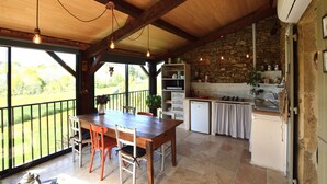 Een eethoek met een houten tafel en stoelen, een keuken met stenen muren, en uitzicht op de omgeving.