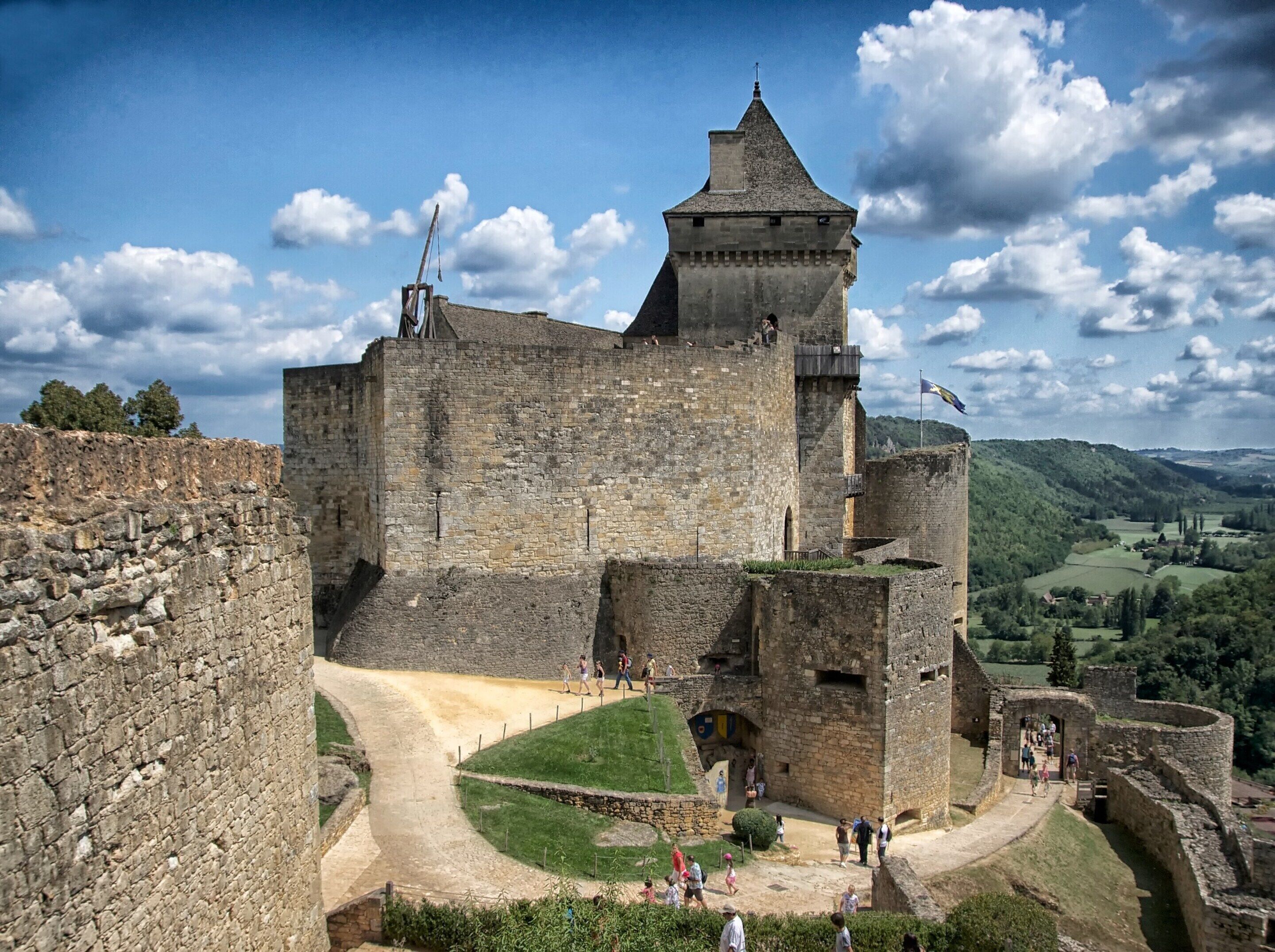 A historic stone castle with a central tower, a surrounding moat, and a pathway leading to the entrance.