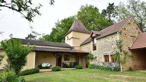 Ein Haus aus Stein mit Ziegeldach, einer Veranda und einem Rasen.