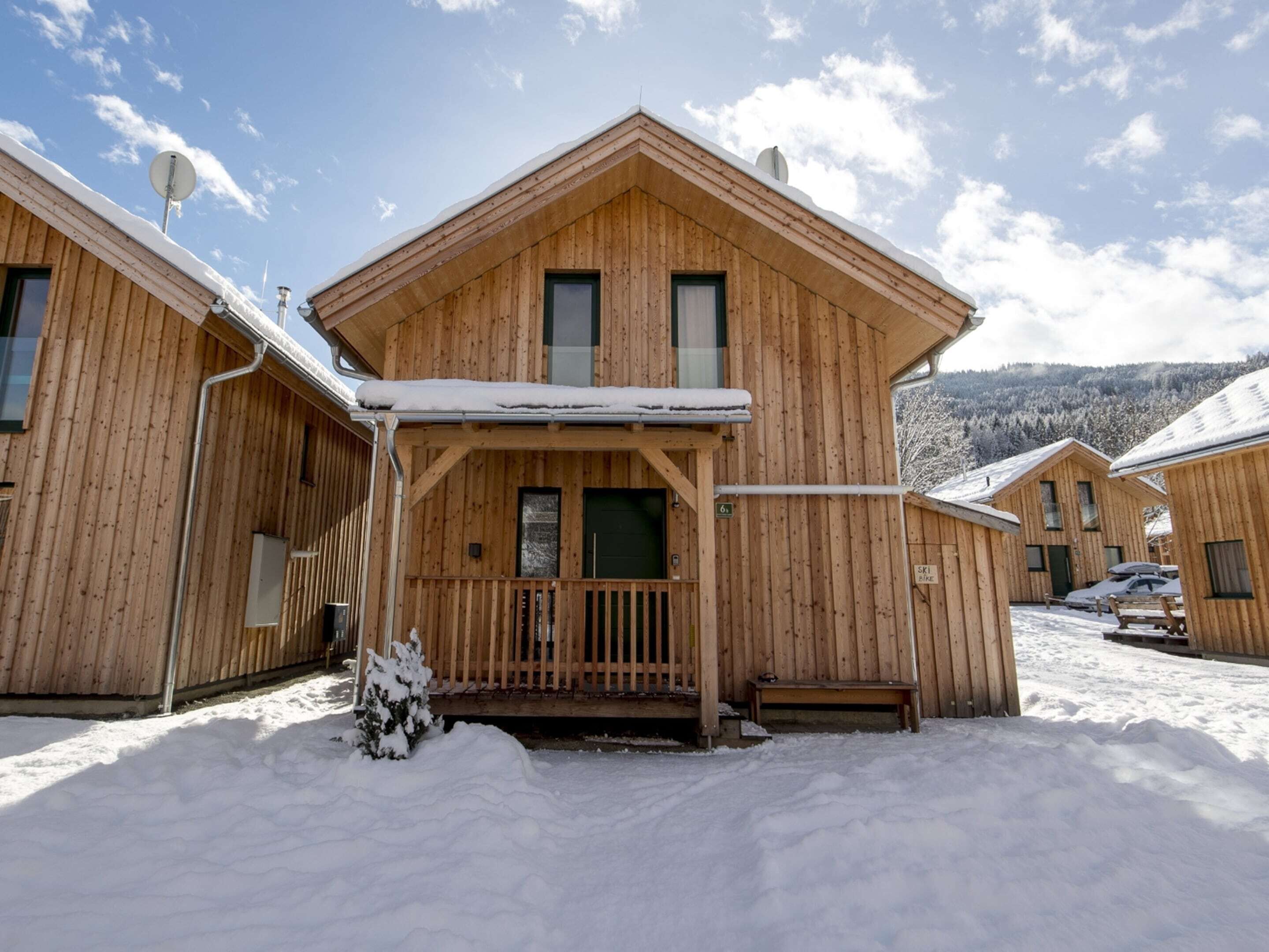 A wooden lodge with a covered porch, multiple windows, and a ski slope sign.