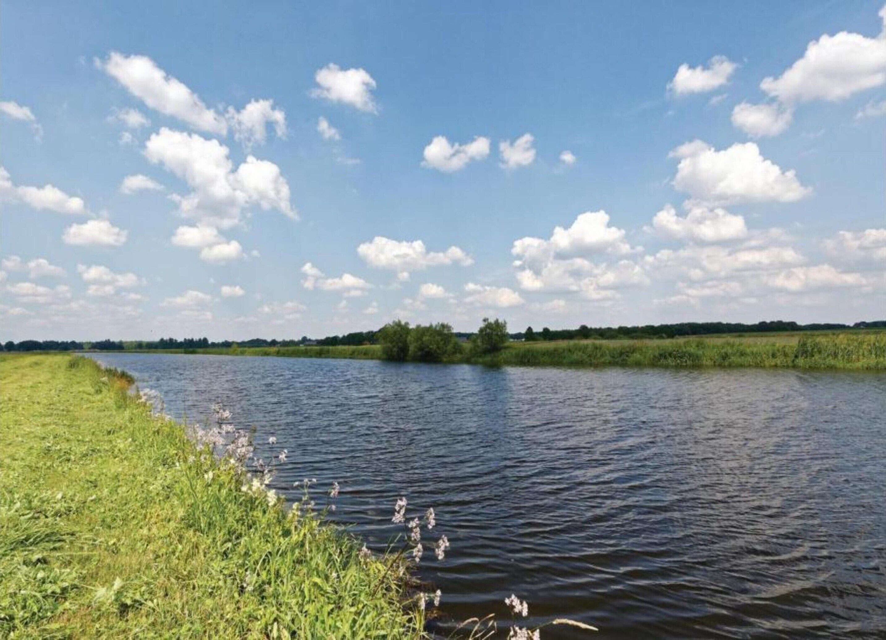 A calm river with grassy banks and a clear sky.