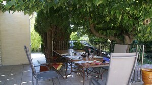 Eine Terrassensitzgelegenheit im Freien mit Esstisch und Stühlen, umgeben von Bäumen.