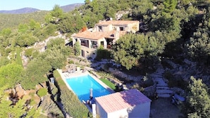 A hillside villa with a swimming pool, terraced garden, and a view of the surrounding landscape. - Villa With Heated Pool, Petanque, spa & View (Villecroze)