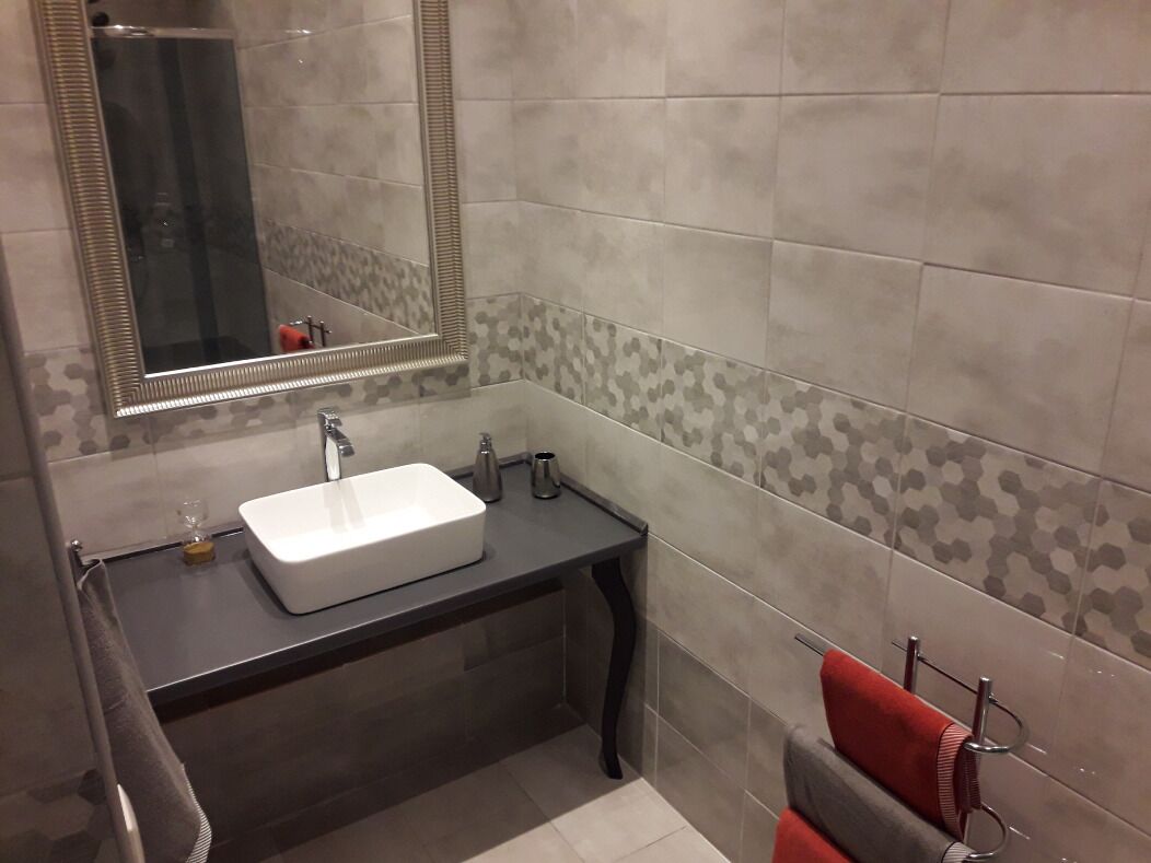 Une salle de bain moderne avec un lavabo blanc, un plan de toilette foncé et un miroir.