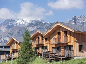 Une rangée de chalets en bois dotés de balcons, se dressant sur fond de montagnes enneigées.