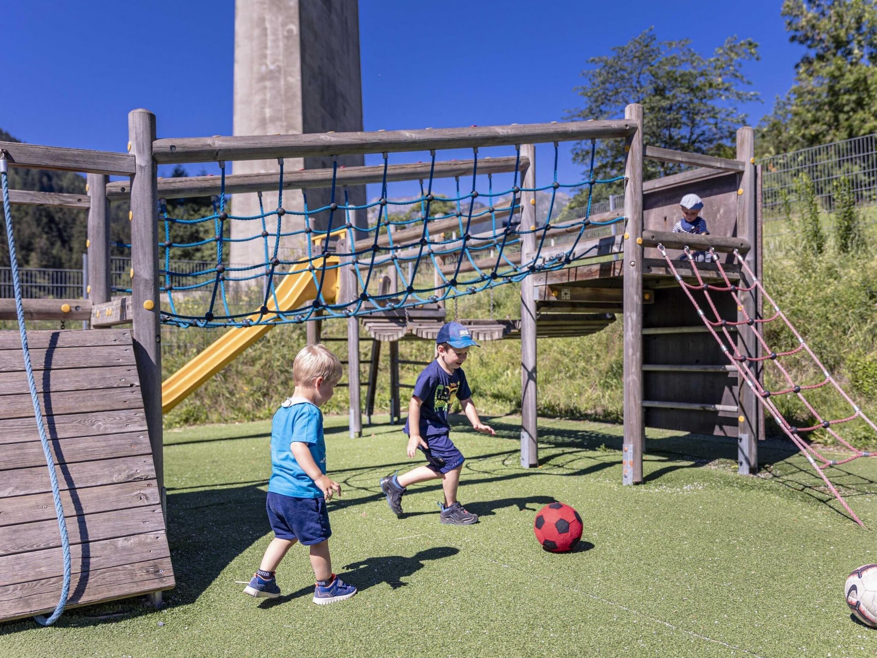 Un parque infantil con una red de cuerdas, un tobogán y una pelota.