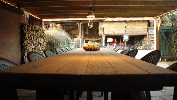 A wooden table with chairs in an outdoor setting, possibly a patio or terrace area.
