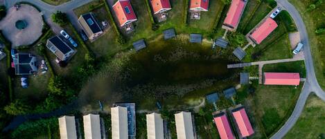 An aerial view of a residential area with houses, a small pond, and a curved road.