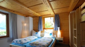 Une chambre à coucher dans une cabane en bois, avec un lit, deux tables de chevet, une fenêtre avec des rideaux et une armoire.