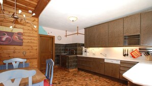 Une cuisine avec des meubles de rangement en bois, un sol en briques et un coin repas comprenant une table et des chaises.