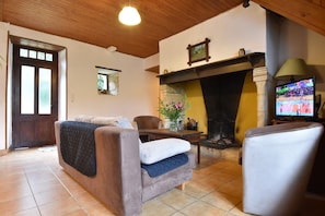 A cozy living room with a sofa, a chair, a fireplace, and a television. - Scenic Home in Berbiguieres (Allas-les-Mines)