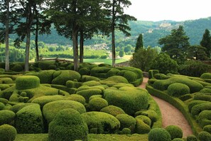 A meticulously landscaped garden with a winding path, surrounded by neatly trimmed hedges and tall trees. - Scenic Home in Berbiguieres (Allas-les-Mines)