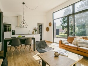 Un espacio habitable moderno con comedor, cocina y un amplio ventanal con vistas al exterior.