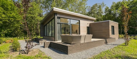 Una casa moderna con facciata in vetro, area relax all'aperto e un giardino.