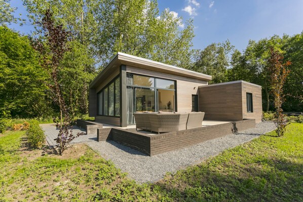 Una casa moderna con fachada de vidrio, mobiliario exterior y jardín.
