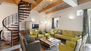 A spacious living area with a spiral staircase, green upholstered sofas, and a wooden coffee table. - Located Near Maastricht Towards the Belgium Border (Eijsden)