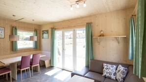 Ein gemütliches Zimmer mit Holzboden, einer Couch, einem Tisch, einem Stuhl und einem Schreibtisch.