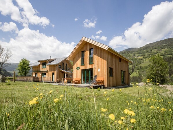 Una cabaña de madera con una amplia terraza y vistas del paisaje circundante.