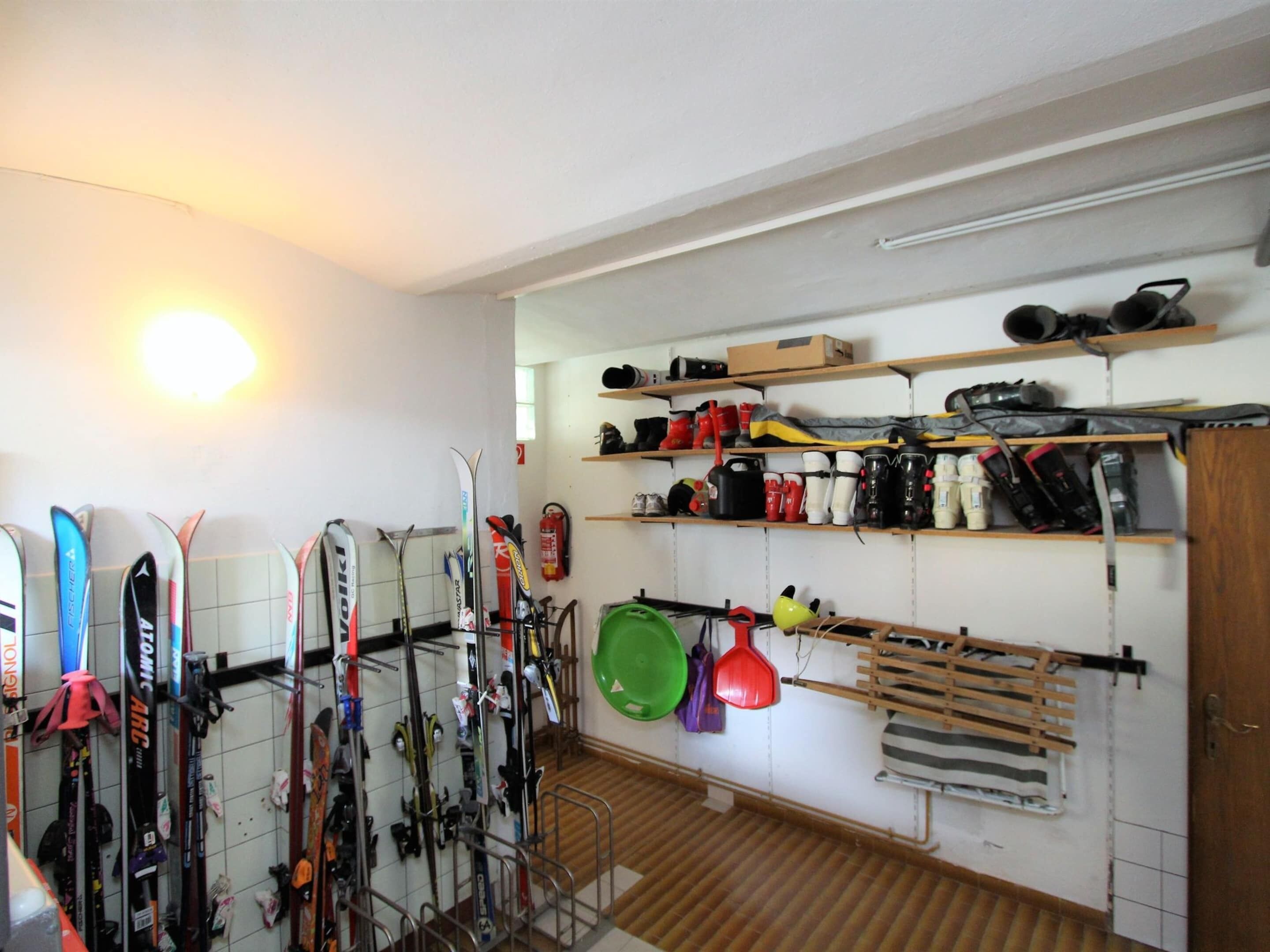 Ein Ski-Abstellraum mit Skiern, Stocken und anderer Wintersportausrüstung.