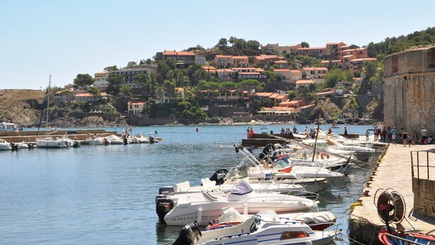 A coastal marina with boats docked, a stone wall, and a hillside with buildings. - Comfortable Villa With Jacuzzi (Montbrun-des-Corbières)