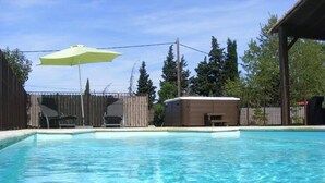 A swimming pool with a wooden deck, a covered hot tub, and a wooden fence. - Comfortable Villa With Jacuzzi (Montbrun-des-Corbières)
