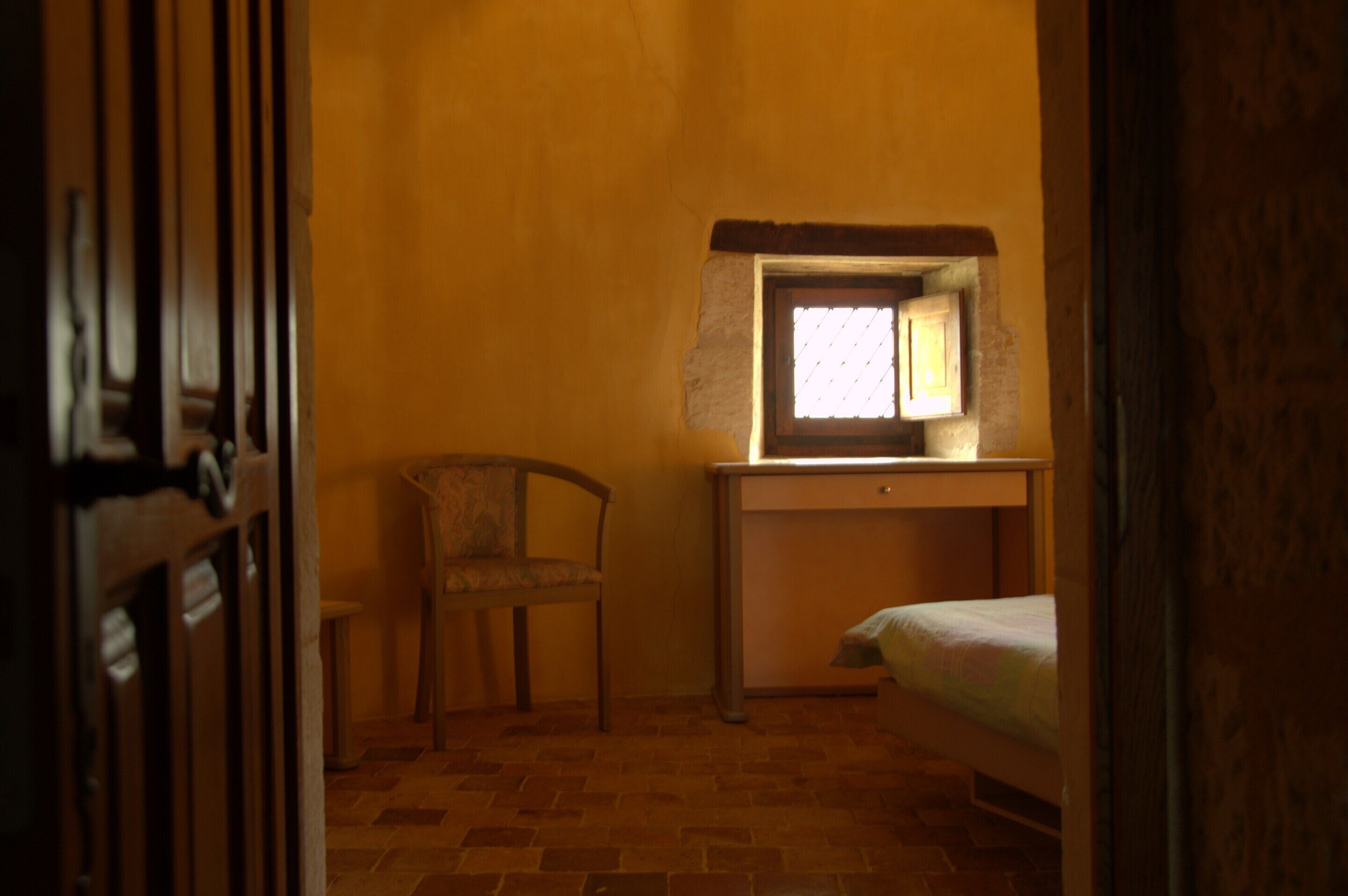 A room with a bed, a desk, a chair, and a window.