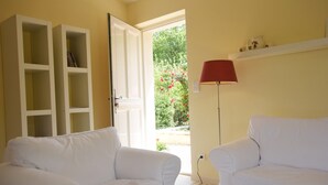 Ein Zimmer mit zwei weißen Sofas, einer weißen Stehlampe und einem Bücherregal.