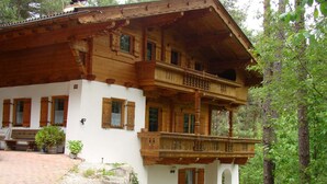 Een houten chalet met een balkon, stenen trappen en een bank.