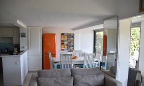 A compact kitchen with white cabinets, a small refrigerator, and a dining area with a table and chairs. - Rural Villa With Shared Pool and Tennis Court (Theoule-sur-Mer)
