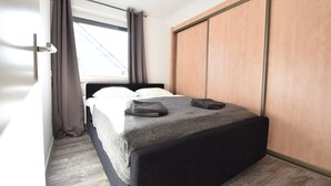 Un dormitorio con cama, ventana con cortinas y armario.