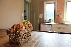 Ein Korbkorb mit Blumen auf einem Holztisch in einer Küche mit Schränken und einem Fenster.